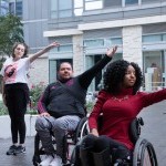 Two disabled and one non-disabled dancer dance together. 