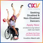 A dancer sits in his wheelchair and lifts another dancer upside down over his shoulder, text application described above. 