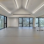 Studio with two large windows and grey marley, a mirrored wall on the right side with a dance bar.