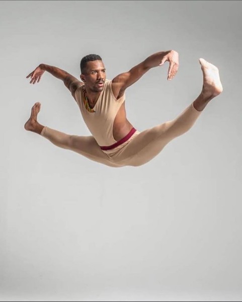 Dancer jumps in the air with limbs stretched to the side
