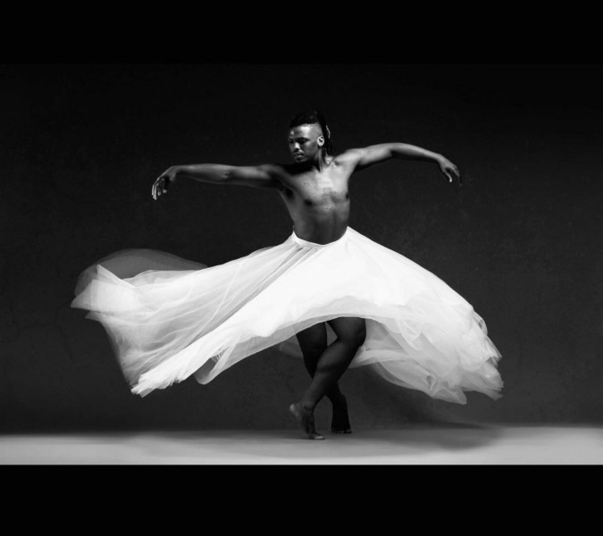 Dancer in white skirt extends their arms wide