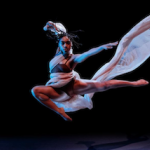 Dancer leaps with fabric thrown 