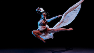 Dancer leaps with fabric thrown 