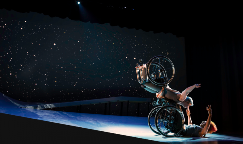 Laurel balances on Alice&rsquo;s footplate, wheels spinning. Alice&rsquo;s arms open wide to embrace her. Light glints off their rims.