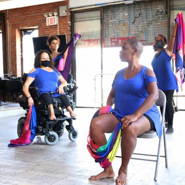 In a dance studio, dancers are dressed in blue and seated.
