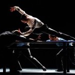 Dancers on stage with one dancer on top of a table