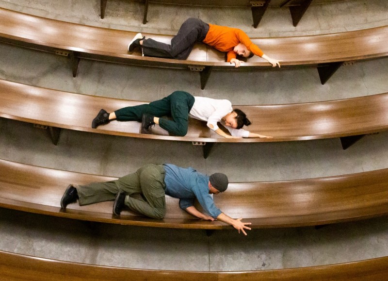 Arial view of 3 pews, one dancer on each facing the same direction in a climbing position. 