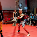 A dancer with hands on a steel I beam