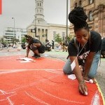 Person drawing with chalk on the ground. 