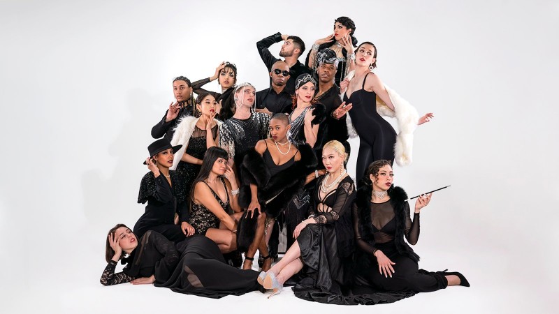 A group of performers in all black strike a pose
