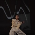 ALT: A dancer in white costume moving gracefully with detailed hand gestures