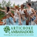 Four people are seen performing outside as they all reach outward with one arm.