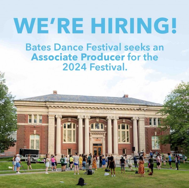 A photo of a large brick building on green grass, surrounded by a crowd.