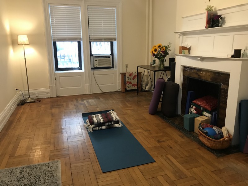 Hardwood floor, yoga props, two windows, mantle.