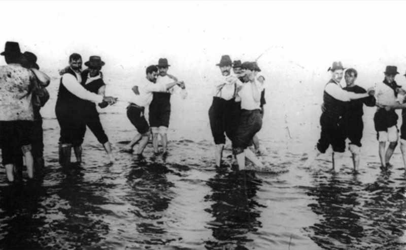 Early 20th century photograph of men dancing together in a body of water
