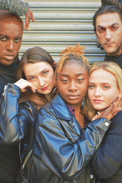 Karma Stylz, Kaitlin Hill, Annia Nelson, Jamie Solomon and Rinor Zymberi wearing black leather and looking straight ahead.
