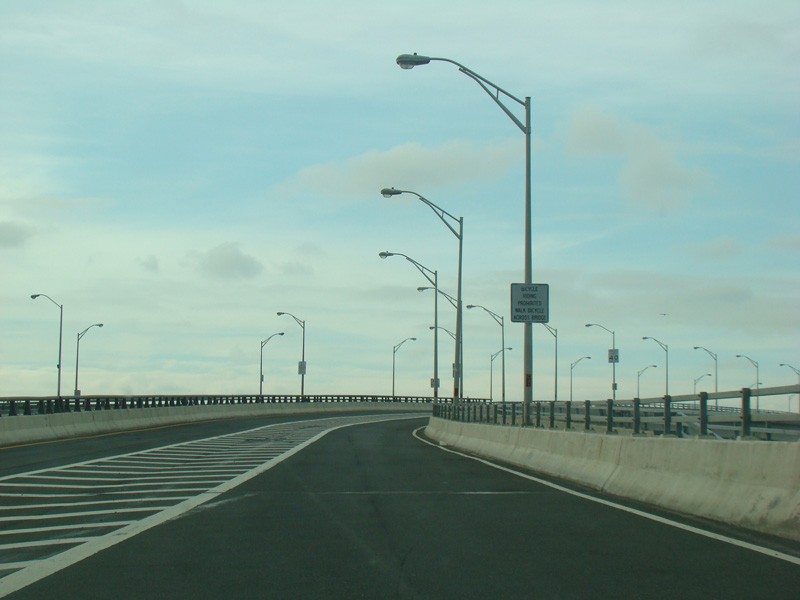 An upwardly sloping bridge with street lights on one side