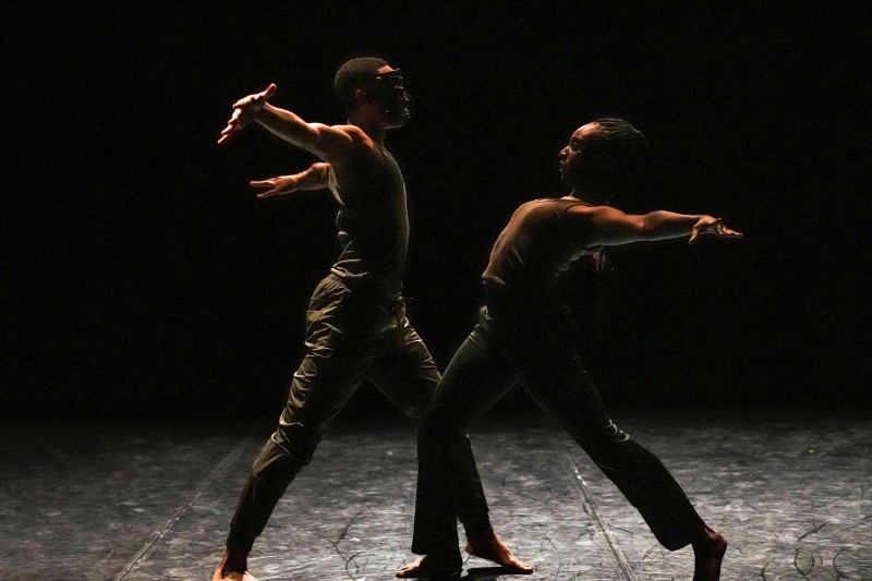 Two dancers, one with an ancient mask, perform a duet, lunging towards each other with their arms thrown back