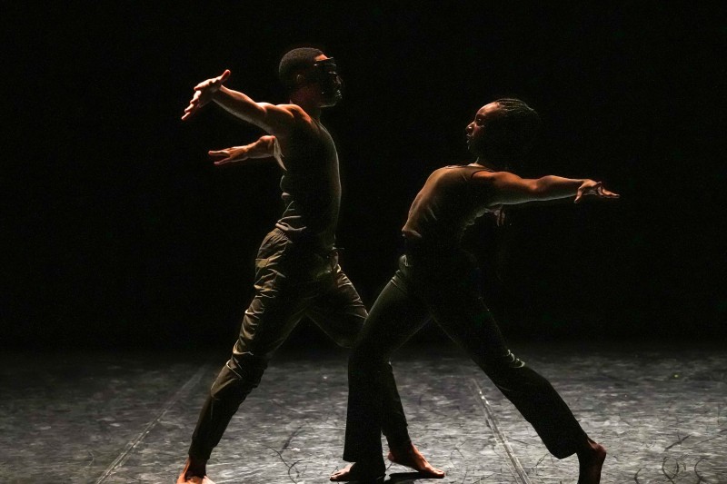 Two dancers, one with an ancient mask, perform a duet, lunging towards each other with their arms thrown back