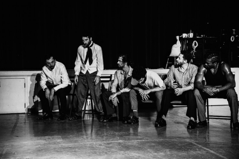 Dancers sitting and standing in a row of chairs