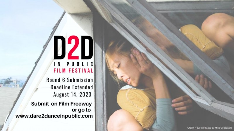 A woman in yellow and blue glances against a half open paint glass window 