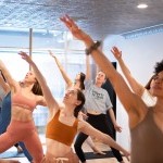 room full of dancers reaching up on a diagonal