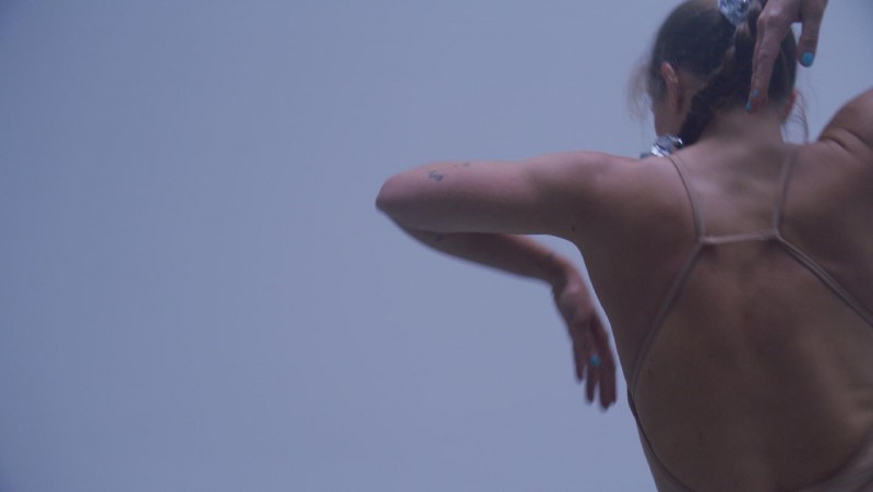 The back of a woman's upper body, arm and torso in movement. 