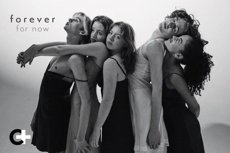A black and white image of five teen performers standing in a line leaning in and against each other with intimate familiarity. 