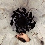 Large white FORMIT fragments fill the image leaving space for a black whole. A white female back emerges from the fragments.