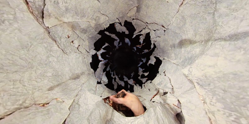 Large white FORMIT fragments fill the image leaving space for a black whole. A white female back emerges from the fragments.