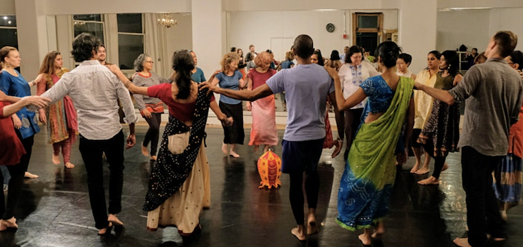 Dance In The Round. We see people forming a circle and dancing joyfullly