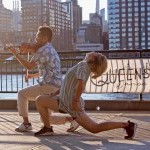 Waterfront show, male dancer playing a violin next to female dancer in backbend