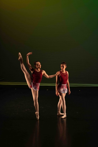 Two dancers on stage, one with leg lifted, the other making a funny face