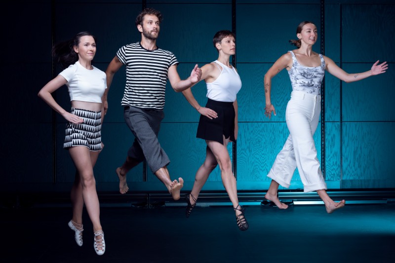 Four dancers mid-movement, as though walking on air.