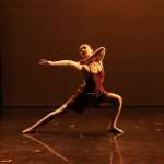 Dancer in a lunge postion, reaching arm to the left.