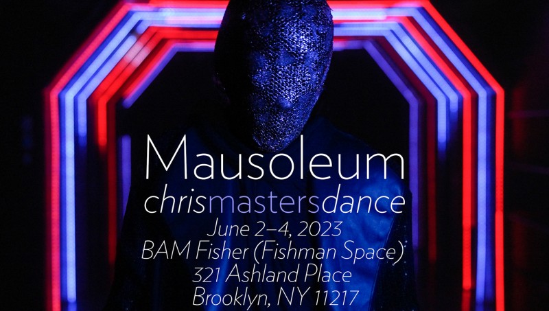 A masked figure in black stands facing camera with a tunnel of multi-colored lights behind them.