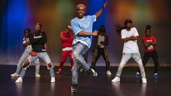 A performance shot of Lil Buck's Memphis Jookin shows a group of 8 dancers on a stage, with Lil Buck positioned in the middle. 