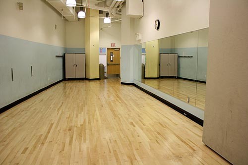 Photo of room, featuring mirror wall and sprung-wood floor