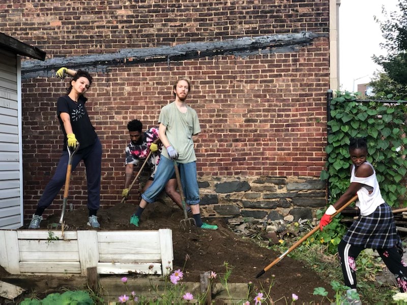 Image representing four dancers, on the pile of dirt in the community garden, facing front, having garden tools in their hands 