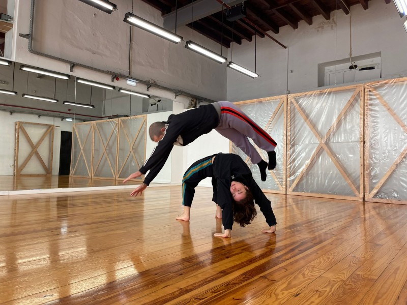 One dancer jumping over another dancer in a studio