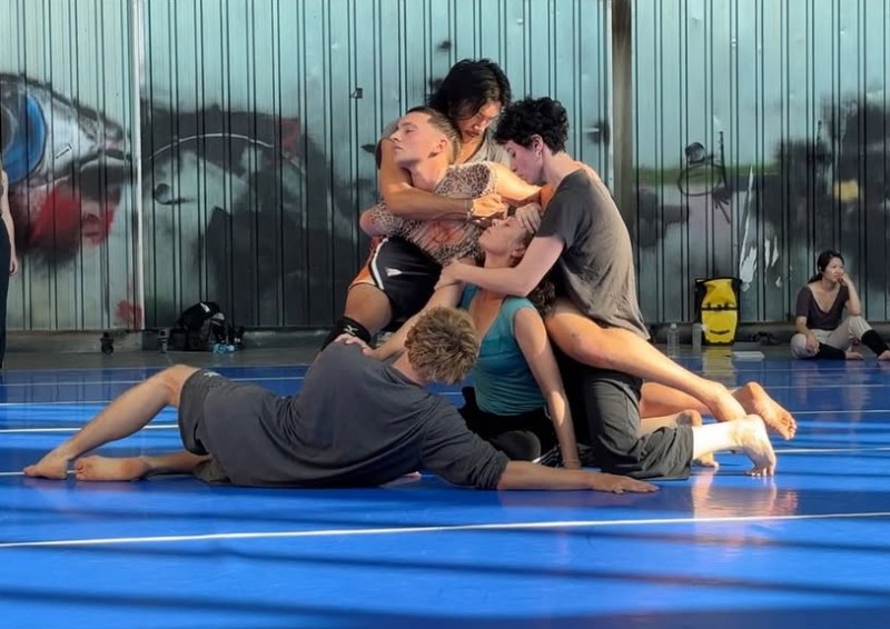 five people tangle and lounge in various positions of holding and being held.