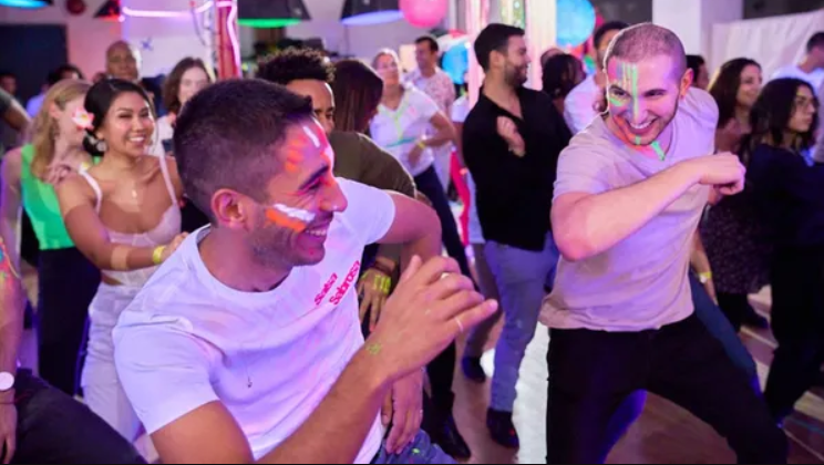 A lively party, people have striped face paint and everyone is dancing