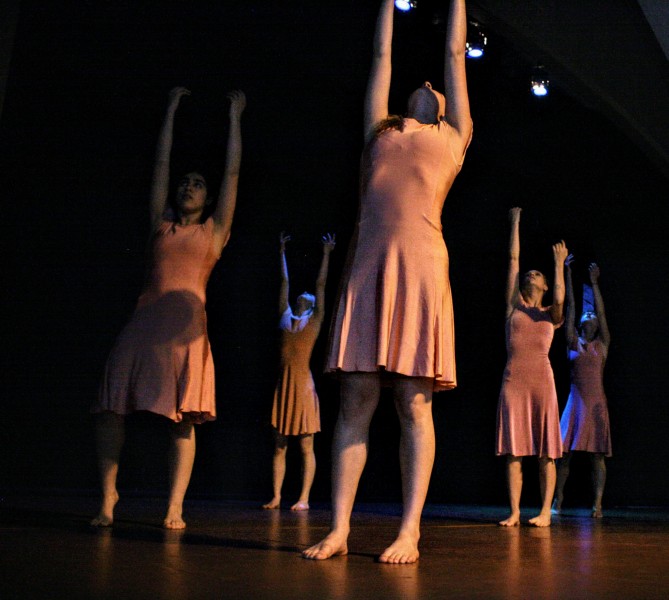 Photo of the work of Paige Nelson at Small Plates Metuchen 2019. Four women in pink dresses stand with arms reaching up.