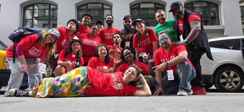 Group of 16 Volunteers and Staff from Formation Team wearing 2025 Red Commemorative tshirts posing for a photo after the parade
