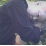 A dancer in white bodypaint/makeup crouching