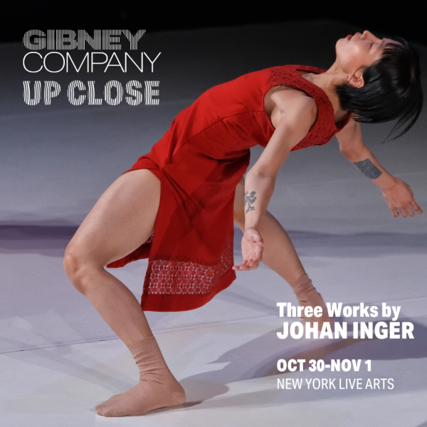 Dancers with short black hair wearing a red dress and tan socks leans back with knees bent, legs apart and arms outstretched