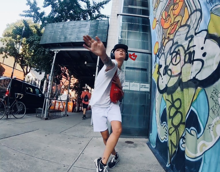 Dancer Alicia Morales poses mid-dance on a Bronx sidewalk, with imagery of graffiti surrounding her to the right