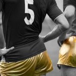 Two dancing soccer players with gold shorts and jerseys seen from the back