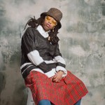 Dancer and workshop facilitator Candice Taylor posing, wearing a red plaid skirt, black and white top, brown hat, and sunglasses