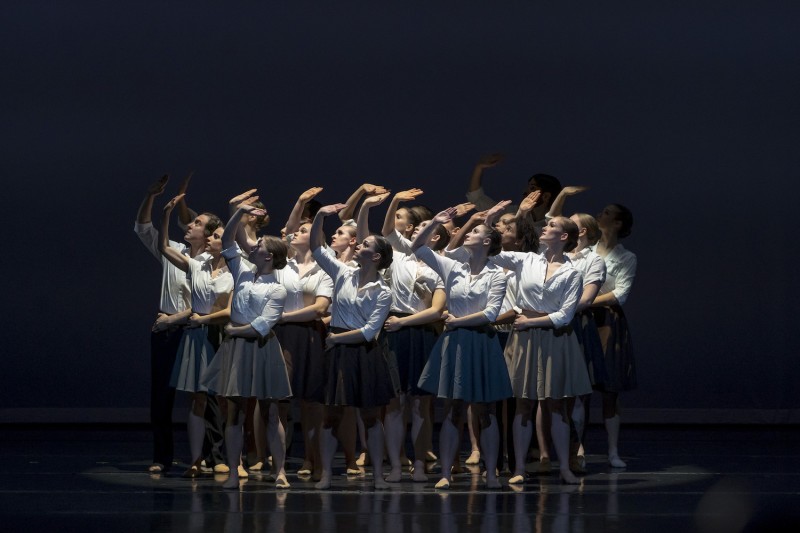 A group of dancers lifts their right arms